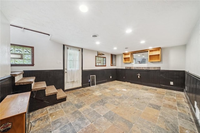 914 Western Ave, Jeannette, PA 15644 - unfurnished living room with stone tile floors, a wainscoted wall, recessed lighting, and wood walls