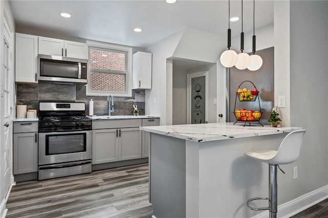 210 E Willock, Brentwood, PA 15227 - kitchen with appliances with stainless steel finishes, a sink, wood finished floors, gray cabinetry, and a kitchen breakfast bar