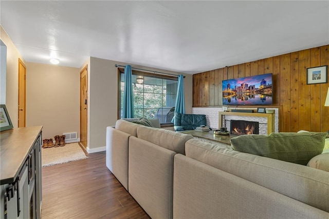 9895 Willow Dr, Mccandless, PA 15090 - living room with dark wood-style floors, a lit fireplace, baseboards, and wooden walls