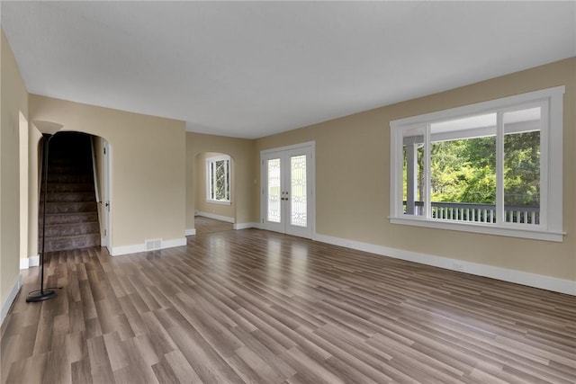 9895 Willow Dr, Mccandless, PA 15090 - unfurnished living room featuring arched walkways, baseboards, wood finished floors, stairway, and french doors