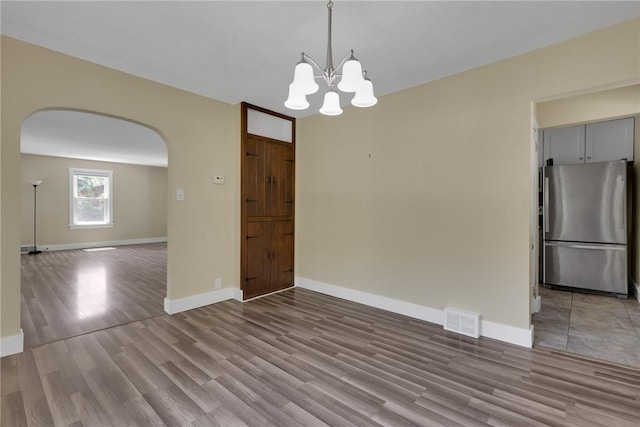 9895 Willow Dr, Mccandless, PA 15090 - unfurnished dining area with arched walkways, wood finished floors, a chandelier, and baseboards