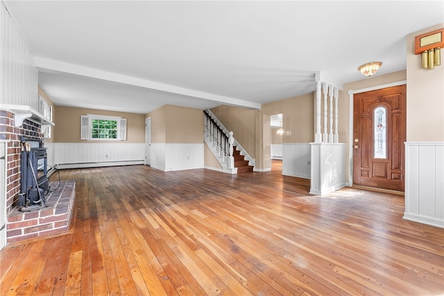 271 Harbison Rd, Buffalo Twp But, PA 16055 - unfurnished living room with hardwood / wood-style floors, a wainscoted wall, a wood stove, stairway, and a baseboard heating unit