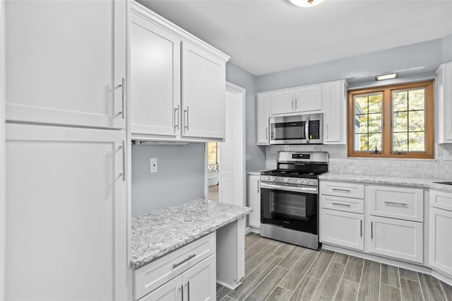 2612 Saybrook Dr, Churchill Boro, PA 15235 - kitchen with appliances with stainless steel finishes, white cabinetry, tasteful backsplash, light wood finished floors, and light stone counters
