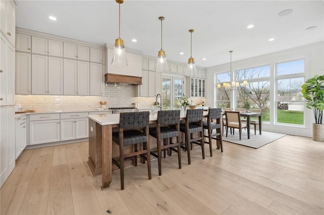 205 Rothaar Ct, Peters Twp, PA 15367 - kitchen featuring light wood-type flooring, decorative backsplash, an island with sink, light countertops, and a kitchen breakfast bar