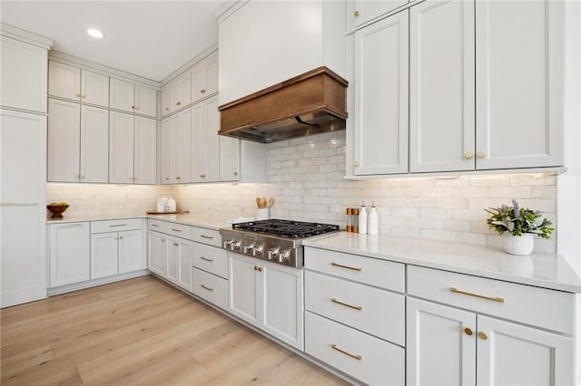 205 Rothaar Ct, Peters Twp, PA 15367 - kitchen featuring stainless steel gas cooktop, light countertops, custom range hood, decorative backsplash, and light wood-style floors