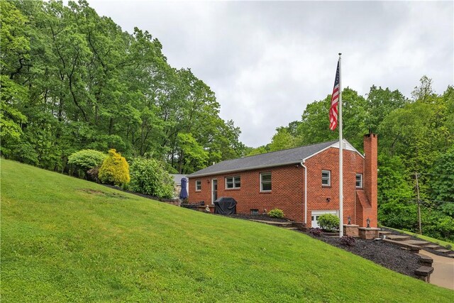 360 Orr Ave, Allegheny Twp, PA 15613 - rear view of property featuring brick siding, a yard, a chimney, and view of wooded area