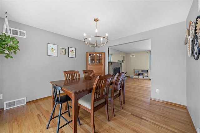 1111 Oriole Dr, Green Tree, PA 15220 - dining space with light wood-style flooring, a chandelier, baseboards, and a brick fireplace