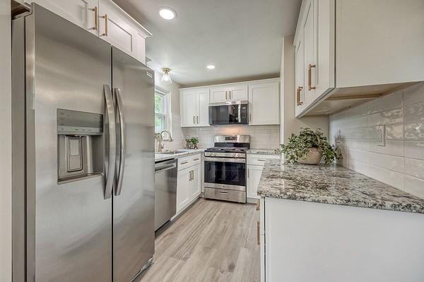 1603 Randolph Ln, Penn Hills, PA 15147 - kitchen featuring stainless steel appliances, a sink, light stone counters, light wood-style floors, and decorative backsplash