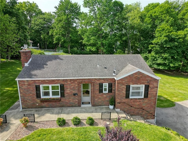 106 Richard Dr, Ross Twp, PA 15237 - view of front of home featuring brick siding, a chimney, a front yard, roof with shingles, and view of scattered trees