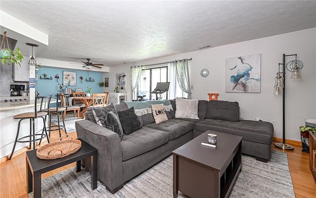 1556 Fairmont St, Wilkinsburg, PA 15221 - living room featuring a textured ceiling, light wood finished floors, ceiling fan, and baseboards