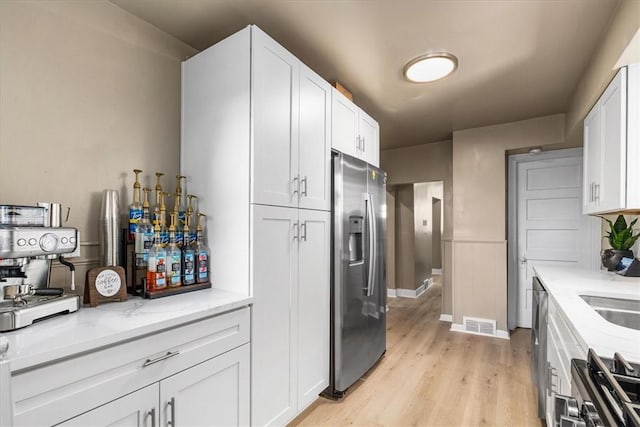 639 Tingley Ave, Bellevue, PA 15202 - kitchen featuring stainless steel appliances, white cabinets, light wood-style flooring, and light stone countertops