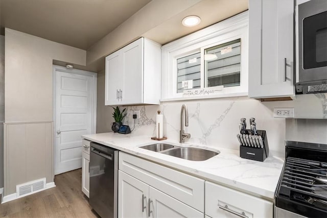 639 Tingley Ave, Bellevue, PA 15202 - kitchen with a sink, stainless steel appliances, white cabinets, light wood finished floors, and light stone counters