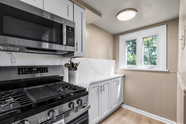 639 Tingley Ave, Bellevue, PA 15202 - kitchen featuring stainless steel appliances, light wood finished floors, light stone countertops, white cabinets, and a wainscoted wall