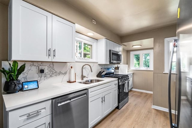 639 Tingley Ave, Bellevue, PA 15202 - kitchen with stainless steel appliances, light wood-style flooring, white cabinets, a sink, and wainscoting