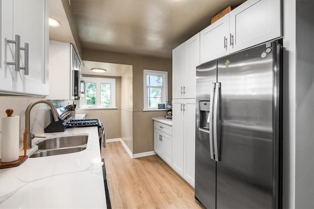 639 Tingley Ave, Bellevue, PA 15202 - kitchen featuring stainless steel appliances, light wood finished floors, a sink, and white cabinetry