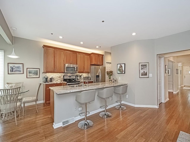 824 Kingsberry Cir, Mt Lebanon, PA 15234 - kitchen with appliances with stainless steel finishes, a kitchen breakfast bar, a peninsula, brown cabinetry, and backsplash