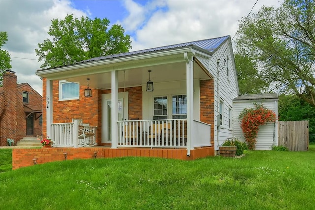 304 Petain St, Ellwood City Law, PA 16117 - view of front of property featuring covered porch, a front yard, metal roof, and brick siding