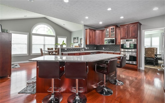 122 Brighton Ln, Adams Twp, PA 16046 - kitchen featuring stainless steel appliances, plenty of natural light, dark wood finished floors, vaulted ceiling, and a textured ceiling