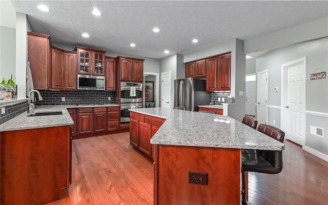 122 Brighton Ln, Adams Twp, PA 16046 - kitchen featuring a sink, appliances with stainless steel finishes, a breakfast bar area, light wood-type flooring, and backsplash