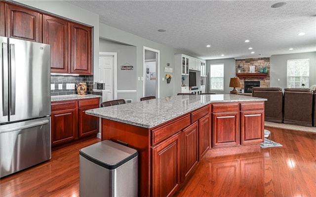 122 Brighton Ln, Adams Twp, PA 16046 - kitchen featuring freestanding refrigerator, a textured ceiling, dark wood-style flooring, a fireplace, and a center island