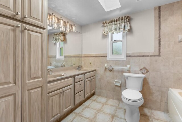 887 E Arcadia Dr, Mccandless, PA 15237 - bathroom with tile walls, a bath, double vanity, wainscoting, and a skylight