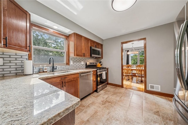 307 Schwartz Ave, Shaler, PA 15209 - kitchen featuring appliances with stainless steel finishes, a sink, brown cabinetry, and light stone counters