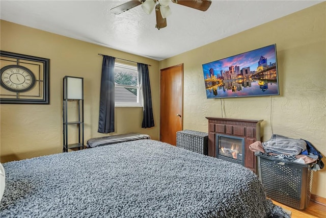 1520 Worcester Dr, Pittsburgh, PA 15243 - bedroom with a textured wall, a glass covered fireplace, ceiling fan, and wood finished floors