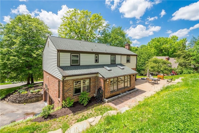 2507 Corteland Dr, Upper St Clair, PA 15241 - rear view of house with brick siding, a patio area, a chimney, roof with shingles, and a lawn