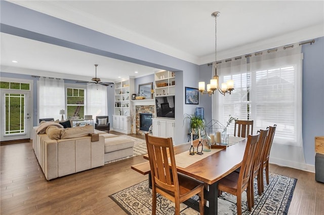 5525 Fontana Ct, Murrysville, PA 15632 - dining room featuring a stone fireplace, wood finished floors, a ceiling fan, a chandelier, and baseboards