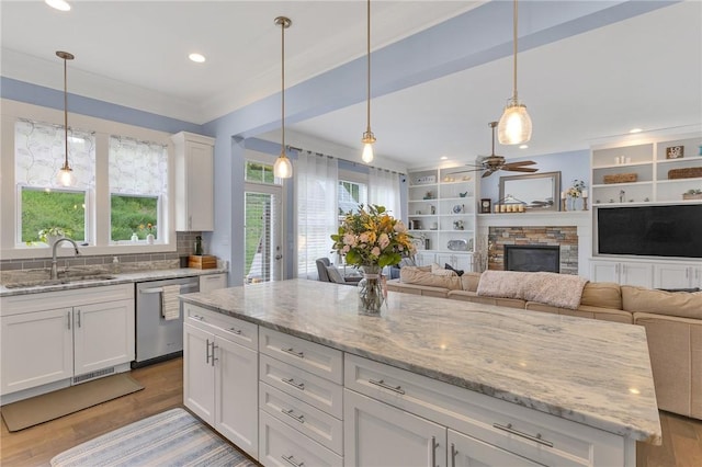 5525 Fontana Ct, Murrysville, PA 15632 - kitchen with a sink, dishwasher, a stone fireplace, light wood-style floors, and white cabinetry