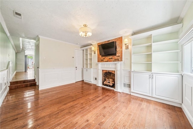 324 Orwell Way, Bloomfield, PA 15224 - unfurnished living room with ornamental molding, a decorative wall, a fireplace, light wood finished floors, and a chandelier