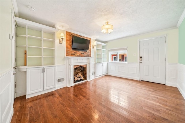 324 Orwell Way, Bloomfield, PA 15224 - unfurnished living room with a textured ceiling, a fireplace, wood finished floors, built in features, and wainscoting