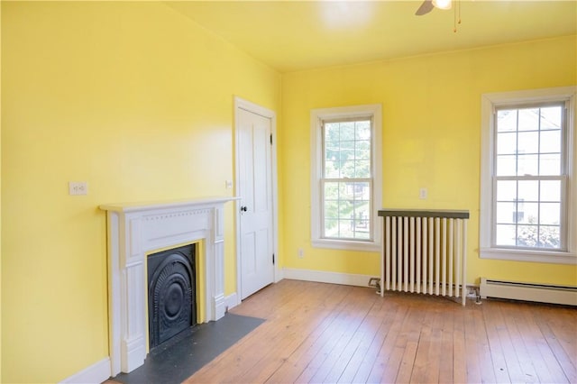 322 Garfield Ave, Mars Boro, PA 16046 - unfurnished living room with a baseboard heating unit, hardwood / wood-style flooring, ceiling fan, a fireplace with flush hearth, and baseboards