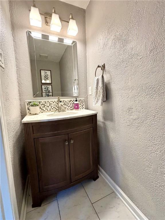 112 Bandywine, Penn Twp Wml, PA 15642 - bathroom with vanity, decorative backsplash, a textured wall, and baseboards