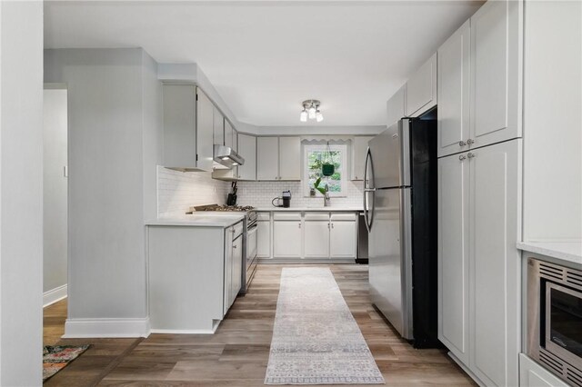 471 Filmore Rd, Forest Hills Boro, PA 15221 - kitchen with stainless steel appliances, range hood, tasteful backsplash, light countertops, and baseboards