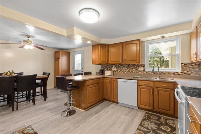 53 Escalon Dr, Findlay Twp, PA 15108 - kitchen featuring white appliances, a sink, a peninsula, a kitchen bar, and brown cabinetry