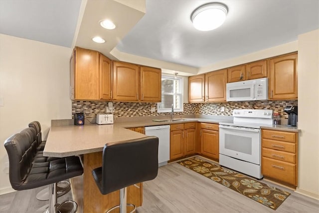 53 Escalon Dr, Findlay Twp, PA 15108 - kitchen with white appliances, a peninsula, a kitchen breakfast bar, a sink, and light wood-style flooring