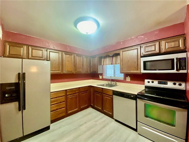109 Parkside Dr, West Mifflin, PA 15122 - kitchen featuring white appliances, a sink, light countertops, brown cabinetry, and light wood-style flooring