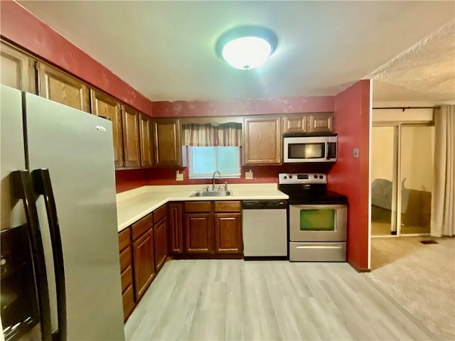 109 Parkside Dr, West Mifflin, PA 15122 - kitchen with appliances with stainless steel finishes, a sink, light countertops, light wood-style floors, and brown cabinetry