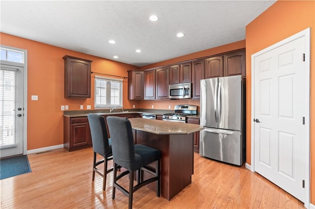 3005 Village Run Rd, Pine Twp Nal, PA 15090 - kitchen featuring appliances with stainless steel finishes, a kitchen bar, a center island, light wood-type flooring, and a textured ceiling
