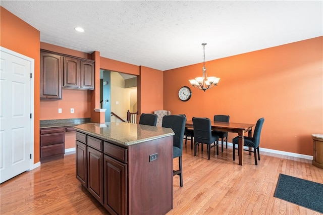 3005 Village Run Rd, Pine Twp Nal, PA 15090 - kitchen with a breakfast bar area, a chandelier, light wood finished floors, a center island, and hanging light fixtures