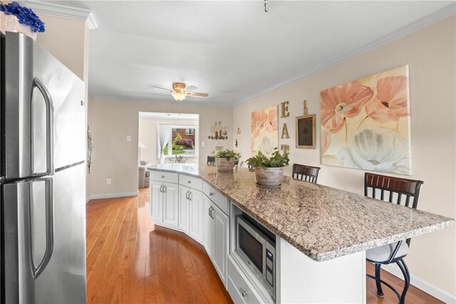 842 Towercrest Dr, Mt Lebanon, PA 15228 - kitchen with stainless steel appliances, baseboards, light wood finished floors, a breakfast bar, and white cabinets