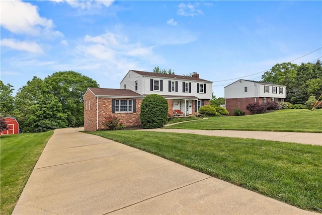 1209 Satellite Cir, Upper St Clair, PA 15241 - view of front facade with brick siding, a front yard, a chimney, and a shed