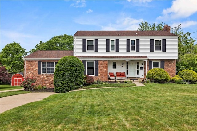 1209 Satellite Cir, Upper St Clair, PA 15241 - view of front facade with covered porch, a chimney, brick siding, and a front lawn