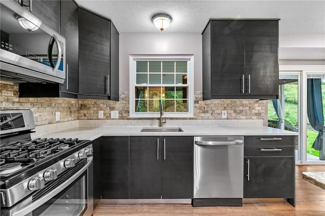 103 Cherokee Ct, Buffalo Twp But, PA 16229 - kitchen featuring stainless steel appliances, a sink, dark cabinetry, light countertops, and tasteful backsplash