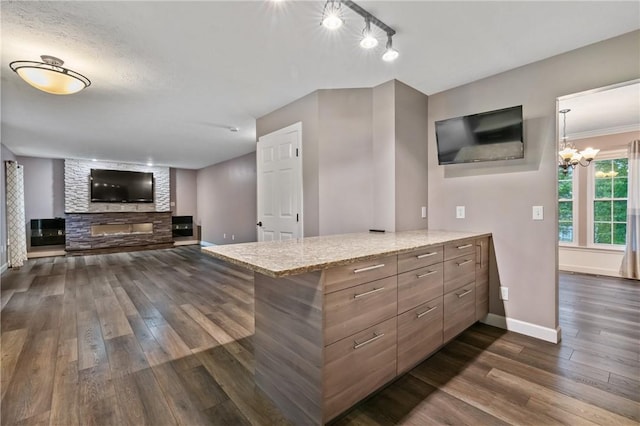 103 Cherokee Ct, Buffalo Twp But, PA 16229 - kitchen with dark wood-style floors, a peninsula, a fireplace, baseboards, and light stone counters