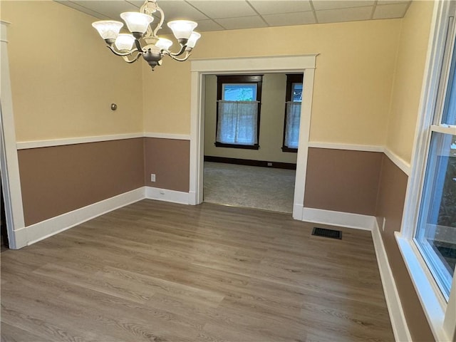 243 Oak St, City Of But Ne, PA 16001 - unfurnished dining area with a chandelier, a paneled ceiling, baseboards, and wood finished floors