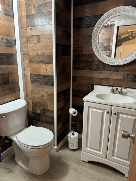 243 Oak St, City Of But Ne, PA 16001 - bathroom with toilet, wood finished floors, wood walls, and vanity