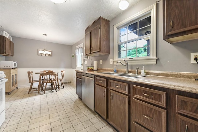 1050 Preston Dr N, Versailles, PA 15137 - kitchen with stainless steel dishwasher, white microwave, a sink, hanging light fixtures, and light tile patterned floors