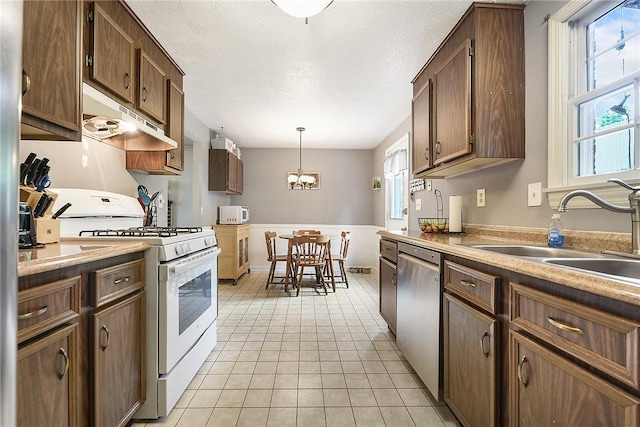 1050 Preston Dr N, Versailles, PA 15137 - kitchen with white appliances, under cabinet range hood, a sink, a chandelier, and hanging light fixtures